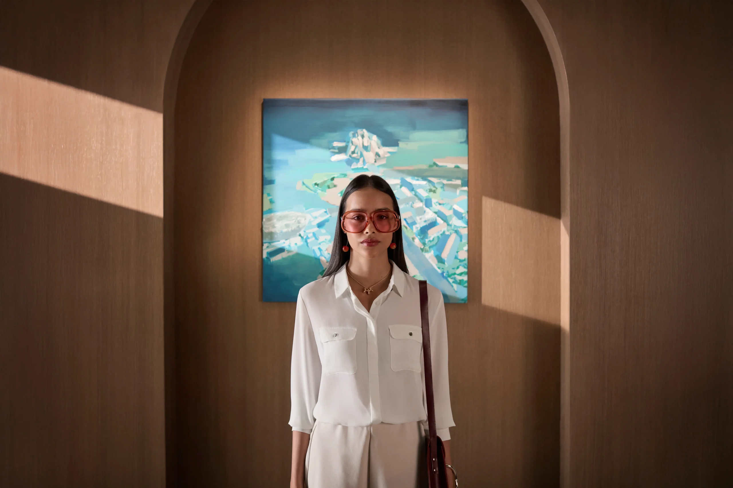 A resident standing in an arched, timber-lined corridor in front of a framed aerial painting